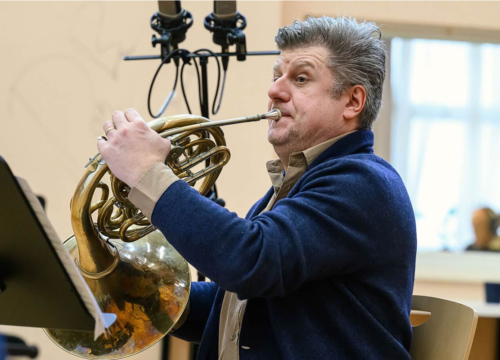 Person plays a french horn in a recording studio.