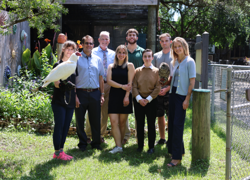 UWF marketing students pose with Wildlife Sanctuary staff. One holds a bird.