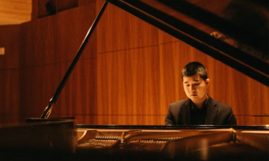 Musician plays piano inside music hall.
