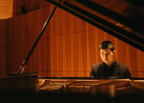 Musician plays piano inside music hall.