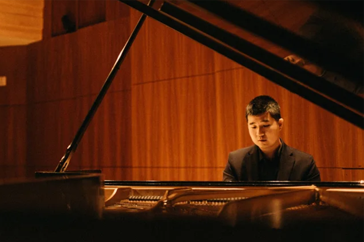 Musician plays piano inside music hall.